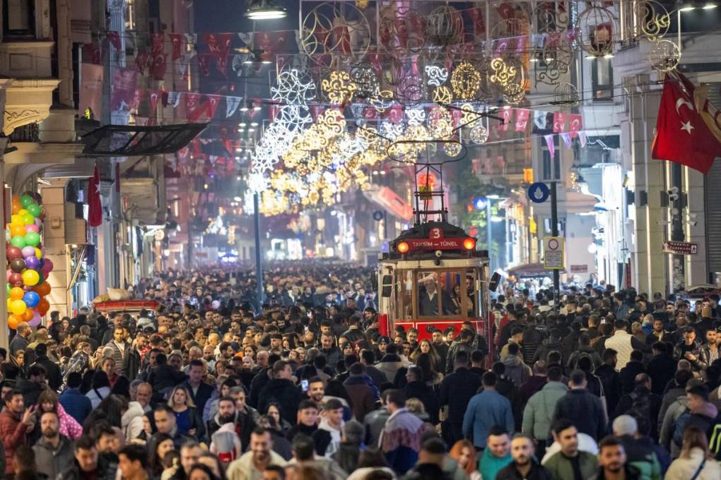 La gente pasa junto a un tranvía histórico bajo decoraciones de luces navideñas en la calle Istiklal durante los preparativos para celebrar el Año Nuevo 2024 en Estambul este 31 de diciembre de 2023.