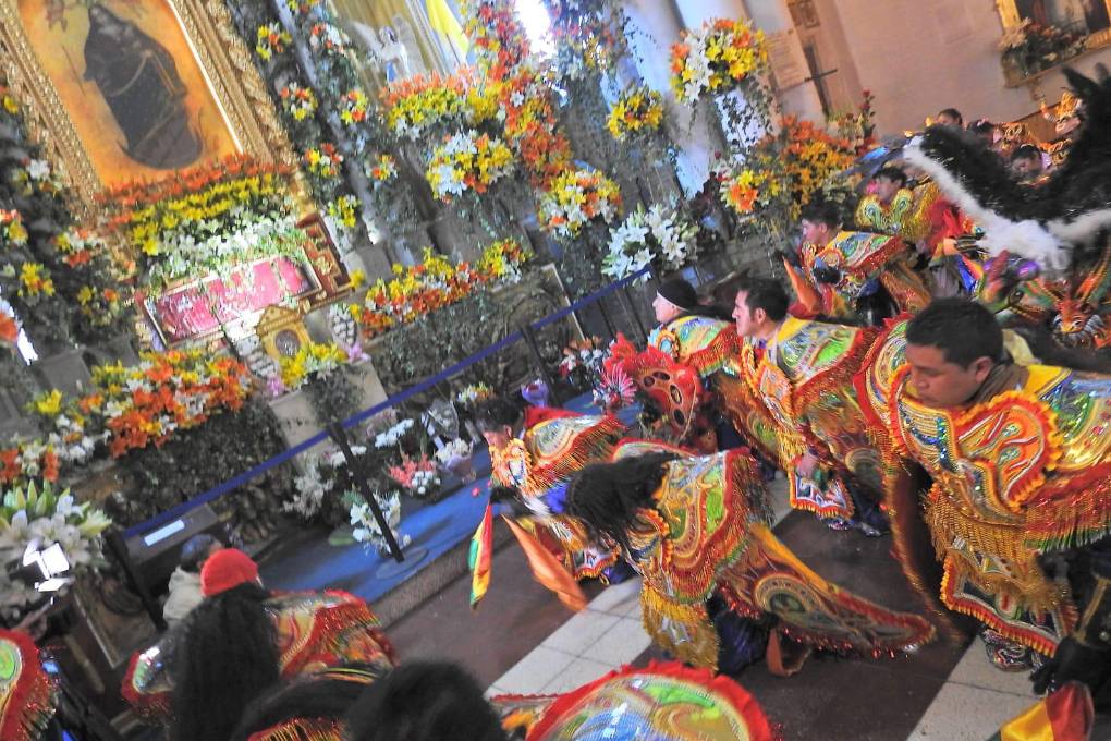 Integrantes de una diablada se arrodillan ante la imagen de la Virgen del Socavón.